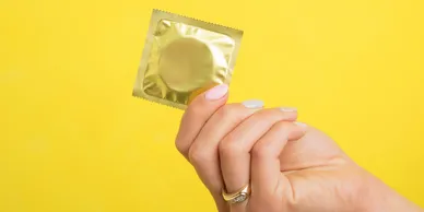 Hand holding a gold condom package.