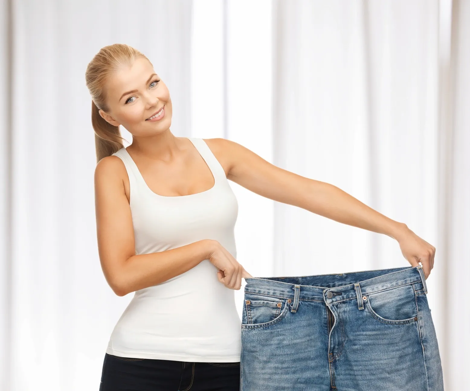 Woman showing large jeans after weight loss.