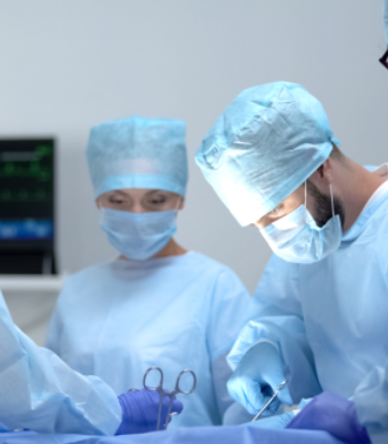Surgeons in blue scrubs performing surgery in an operating room.