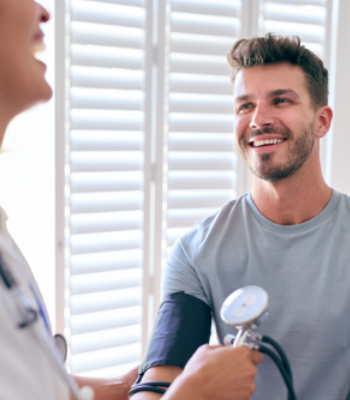 A man smiling while getting his blood pressure checked by a healthcare professional.