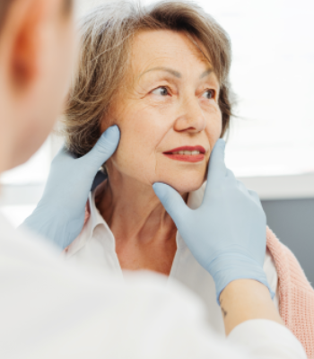 Doctor examining elderly woman's neck for health checkup.