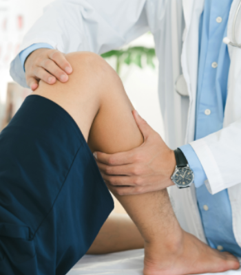 Doctor examining a patient's knee in a medical setting.
