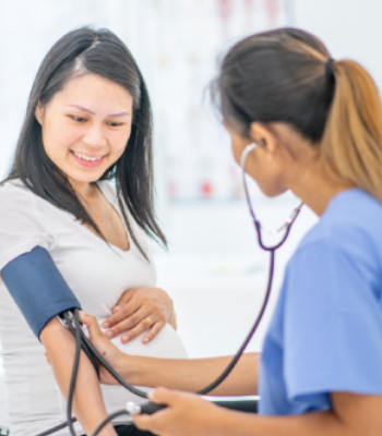 Nurse measuring pregnant woman's blood pressure during check-up.